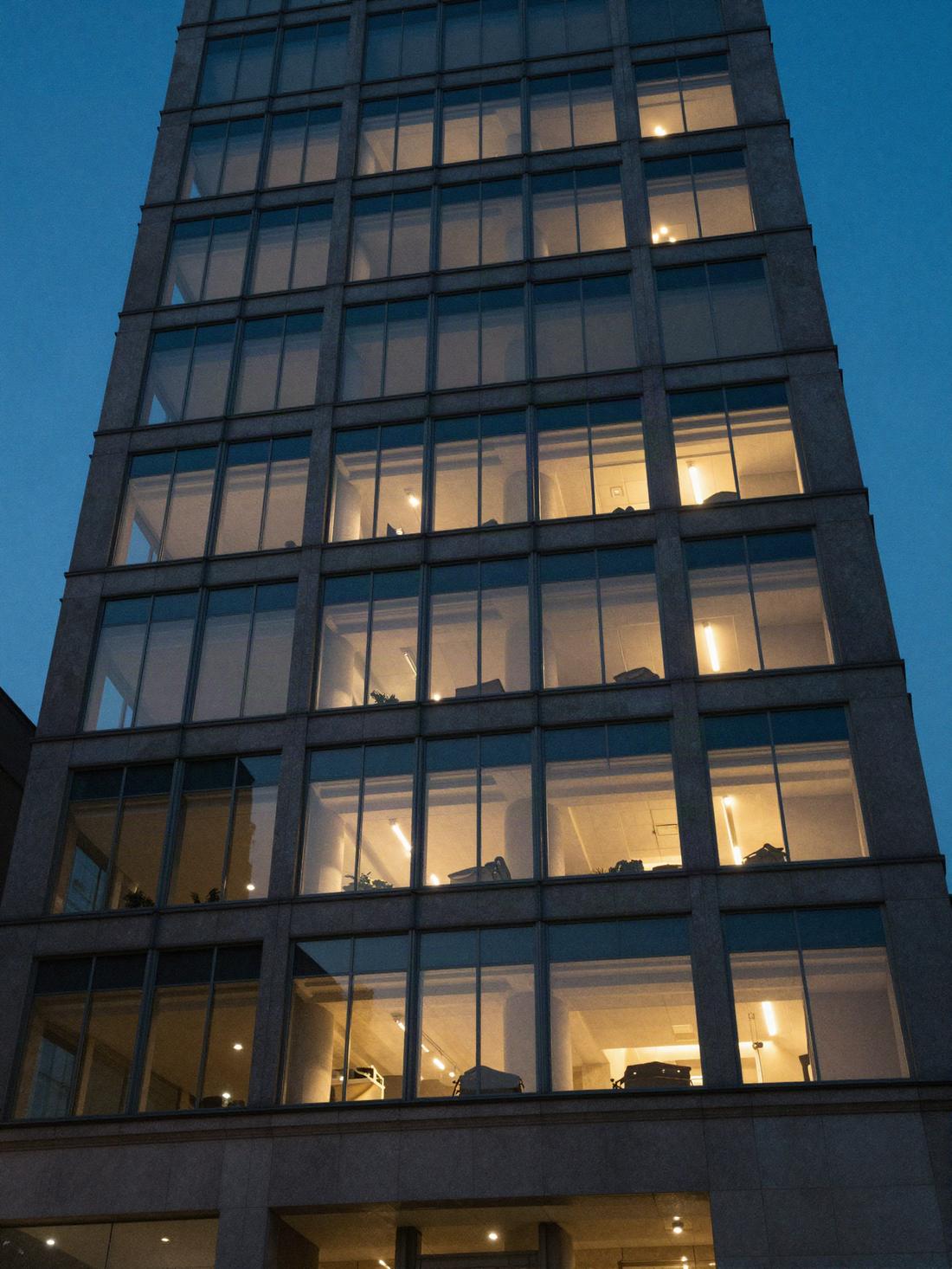 Akşam ışıkları yanan bir ofis binası cephesi